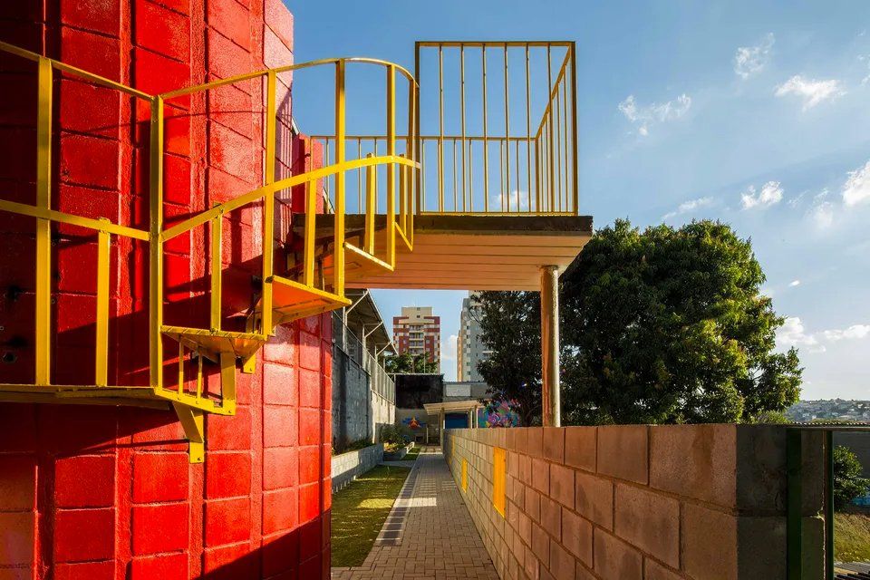 Um prédio vermelho com uma escada amarela que leva a uma varanda.