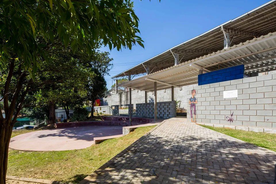 Um prédio de tijolos com uma passarela coberta e uma árvore na frente.