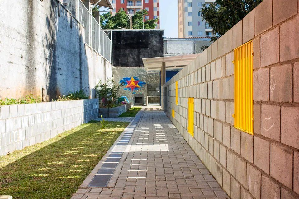 Uma passarela de tijolos que leva a um prédio com uma faixa amarela na lateral.