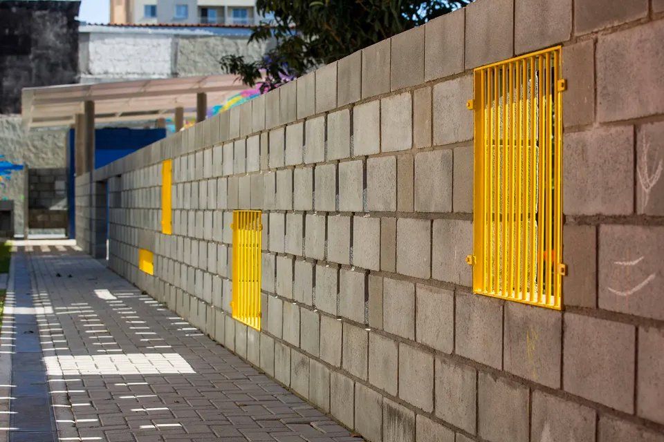 Uma parede de tijolos com janelas e grades amarelas