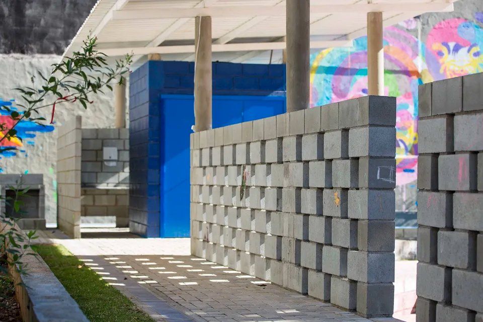 Uma parede de tijolos com uma porta azul ao fundo.