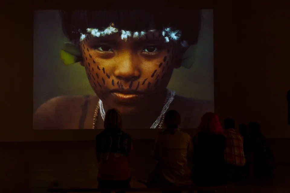 Um grupo de pessoas está assistindo a um filme em uma tela de projetor.