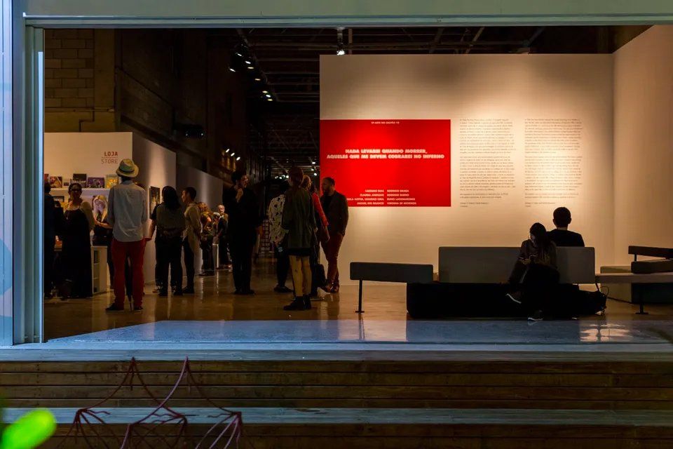 Um grupo de pessoas está em uma sala com uma parede vermelha.