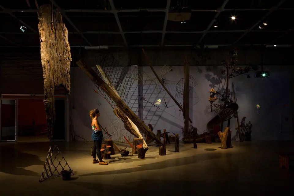 Uma mulher está diante de uma grande escultura em um quarto escuro.