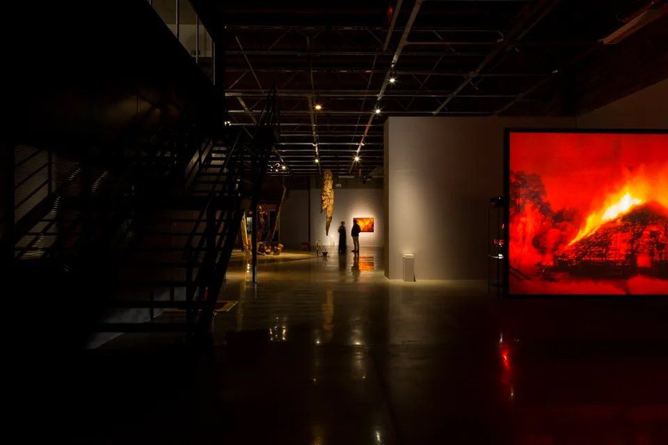Um grupo de pessoas está em uma sala escura em frente a uma grande tela vermelha.