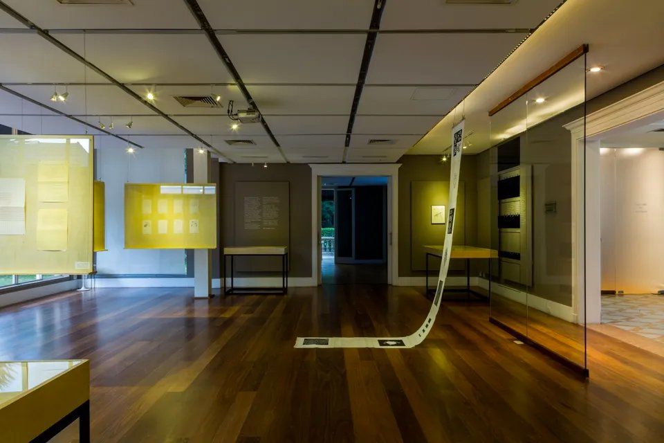 Uma grande sala vazia com piso de madeira e um grande pedaço de papel no chão.