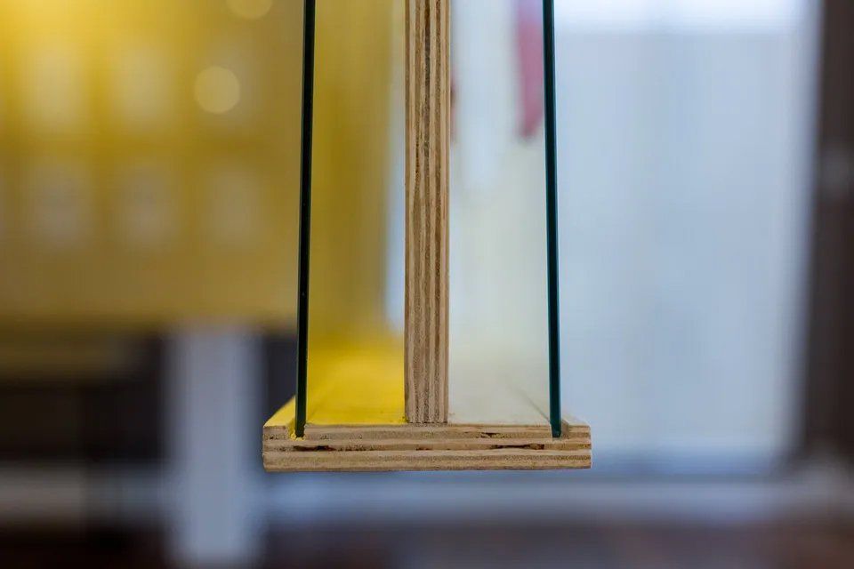 Um close de um pedaço de madeira compensada com uma prateleira de vidro presa a ele.