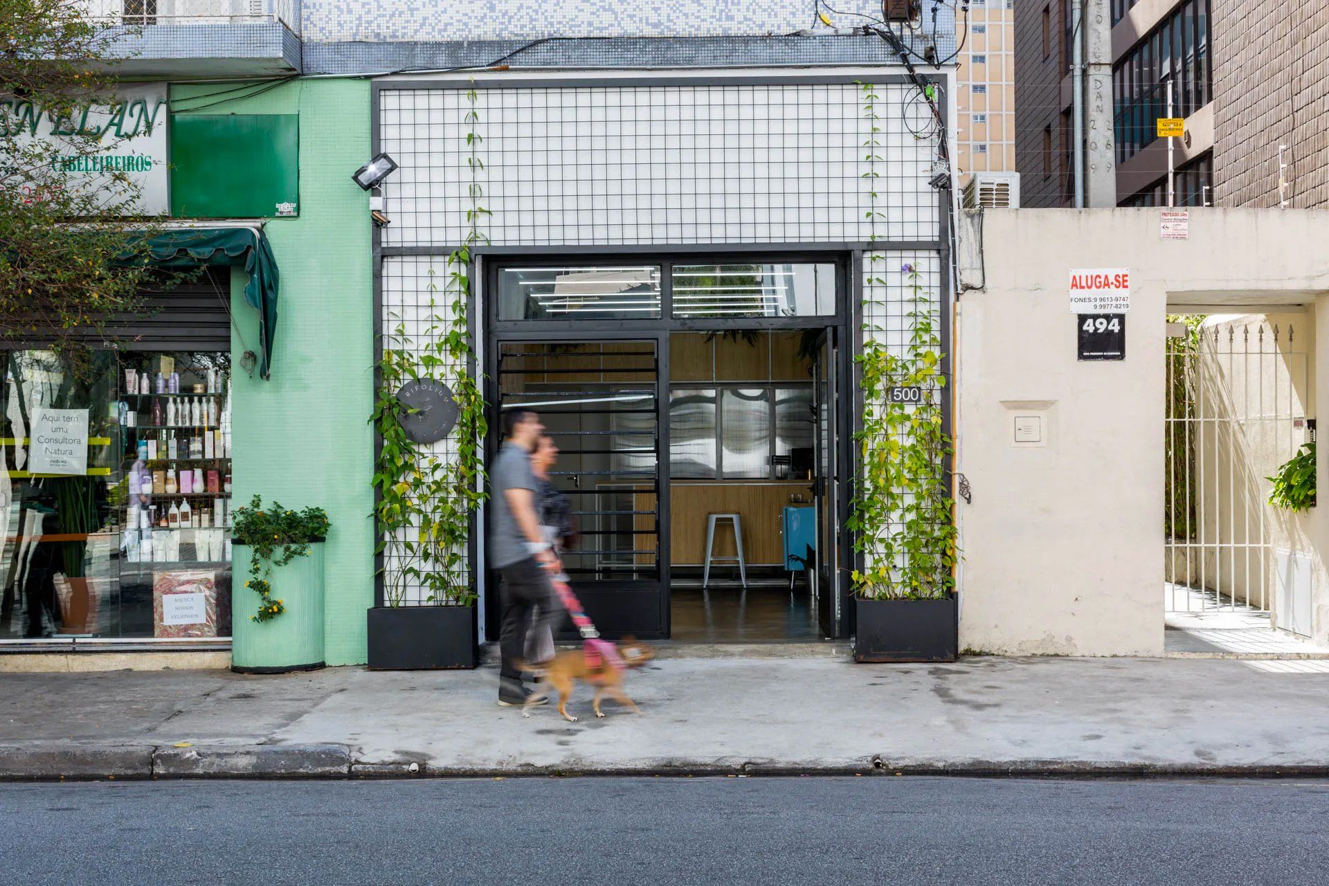 Um homem está passeando com um cachorro na frente de um prédio.