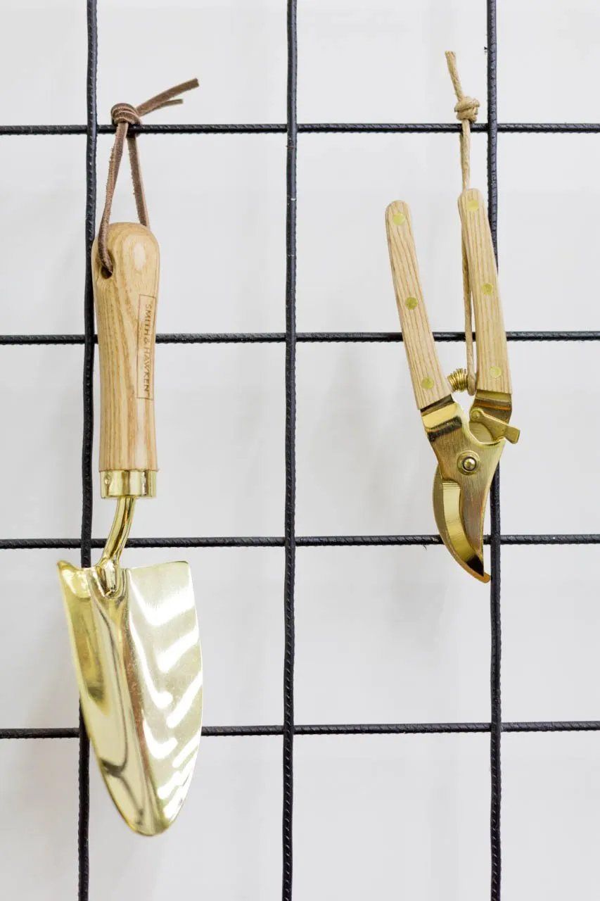 Uma pá e uma tesoura estão penduradas na parede.