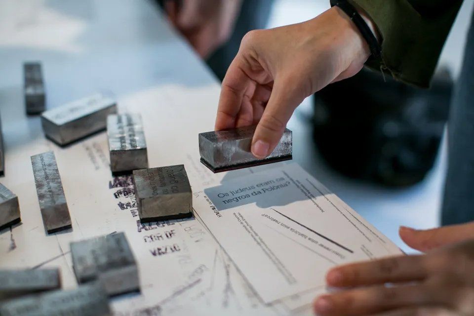 Uma pessoa está segurando um pedaço de metal em cima de um pedaço de papel.