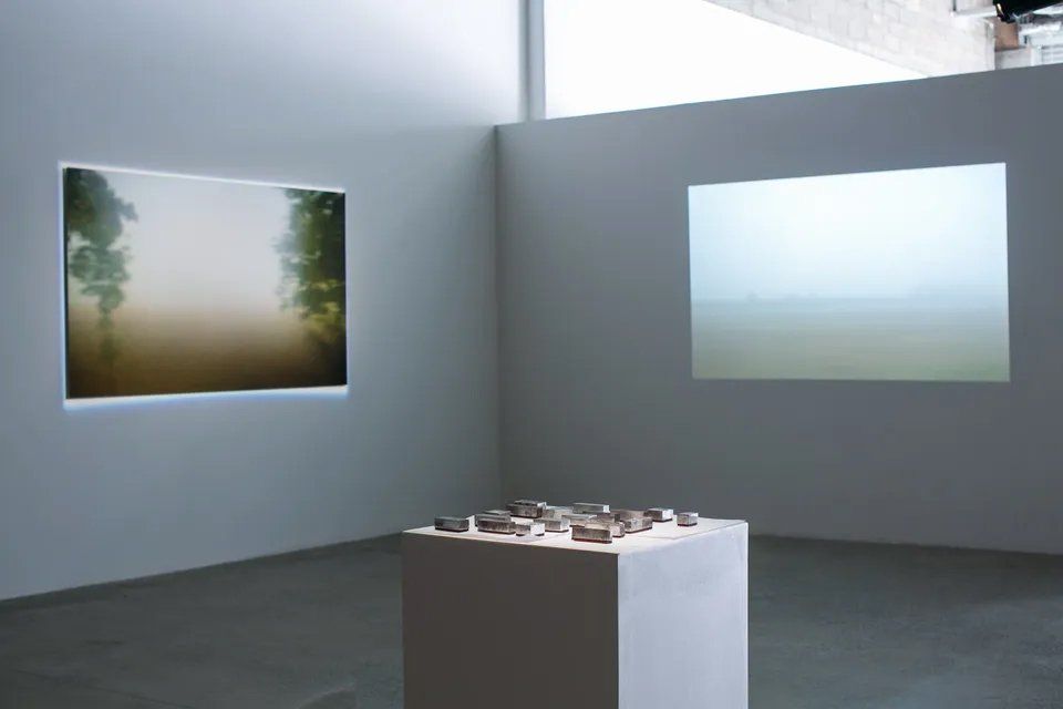 Uma sala com duas pinturas na parede e um cubo no meio