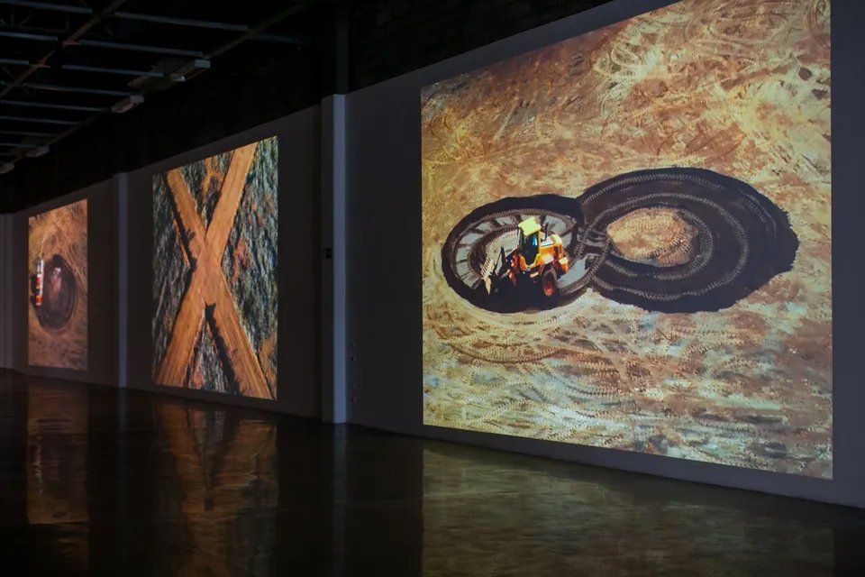 Uma fileira de pinturas na parede de um quarto escuro.