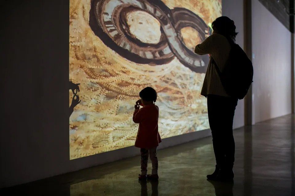 Um homem e uma menina estão olhando para uma pintura na parede.