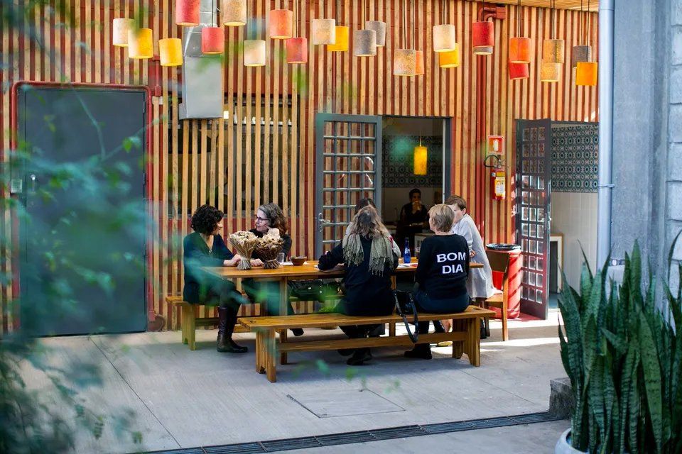 Um grupo de pessoas está sentado em uma mesa de piquenique do lado de fora de um restaurante.