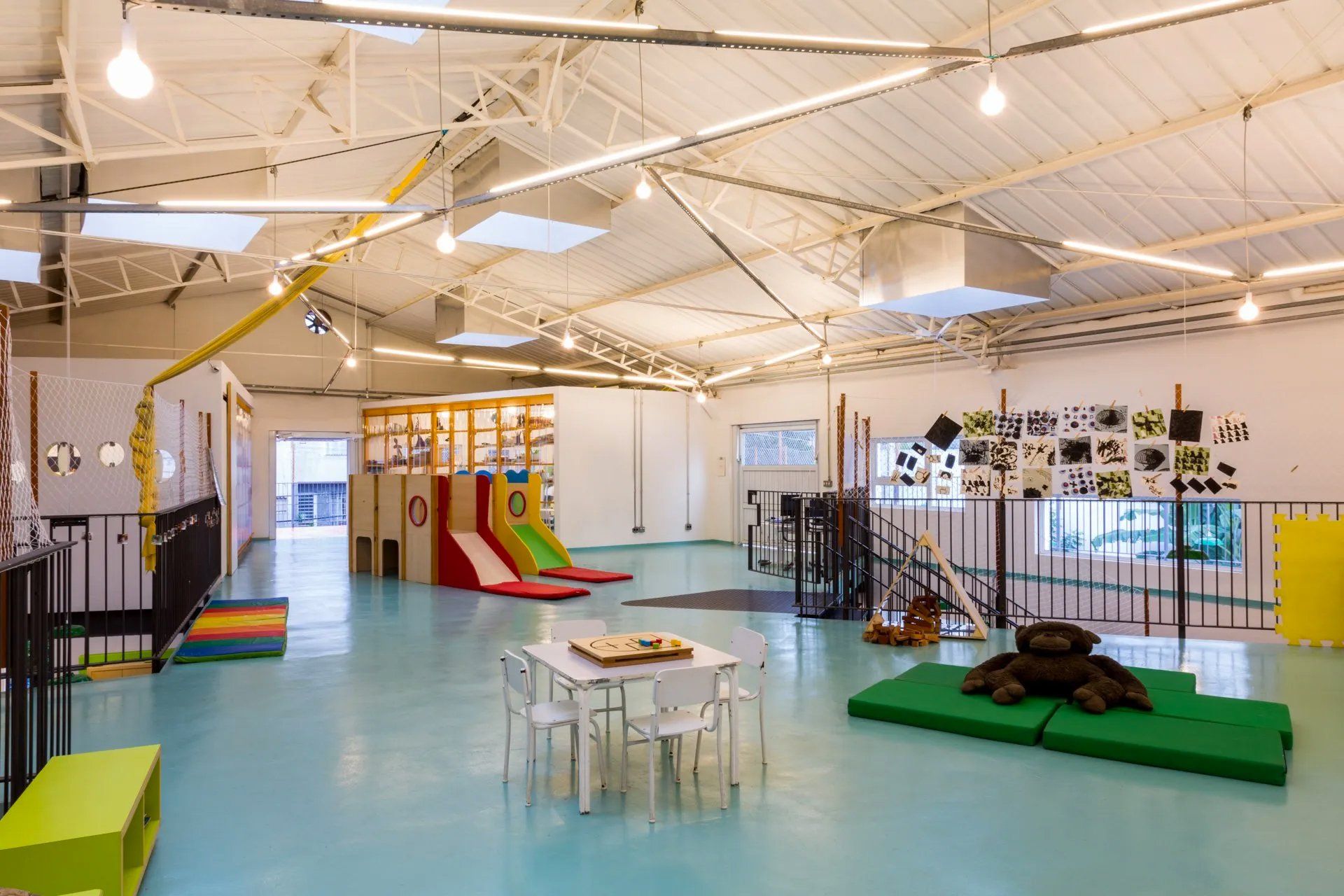 Uma grande sala com mesas, cadeiras e um escorregador.