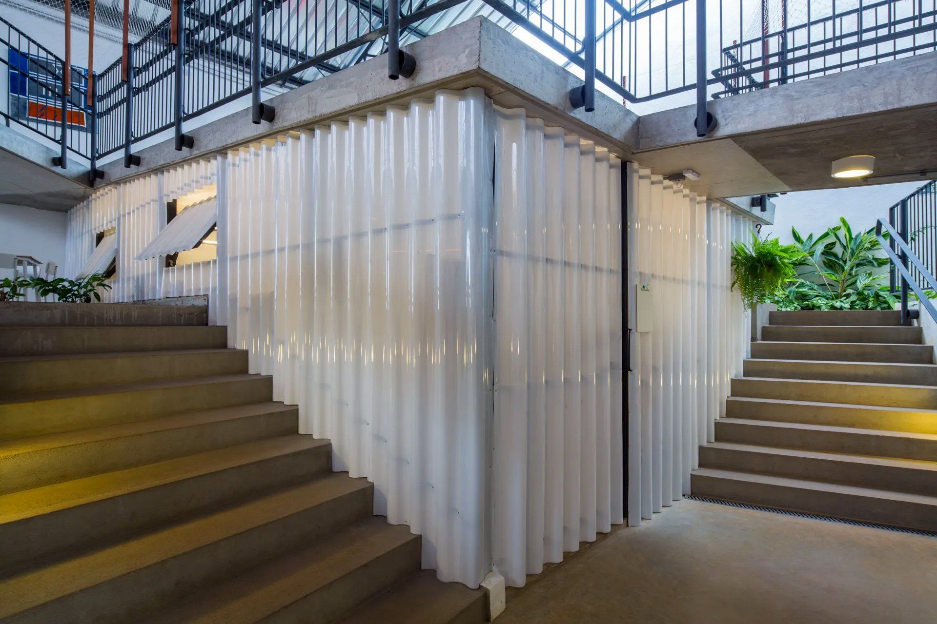 Um lance de escadas que leva a um prédio com parede branca.