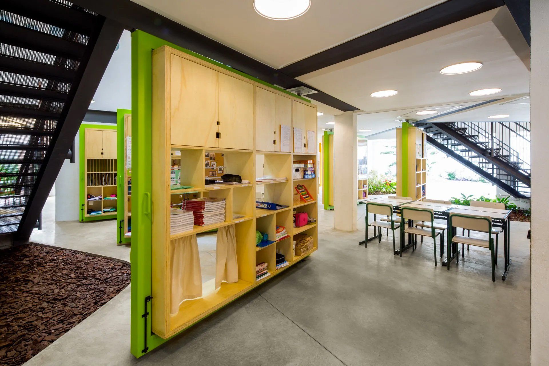 Uma sala com mesas e cadeiras e uma escada ao fundo.