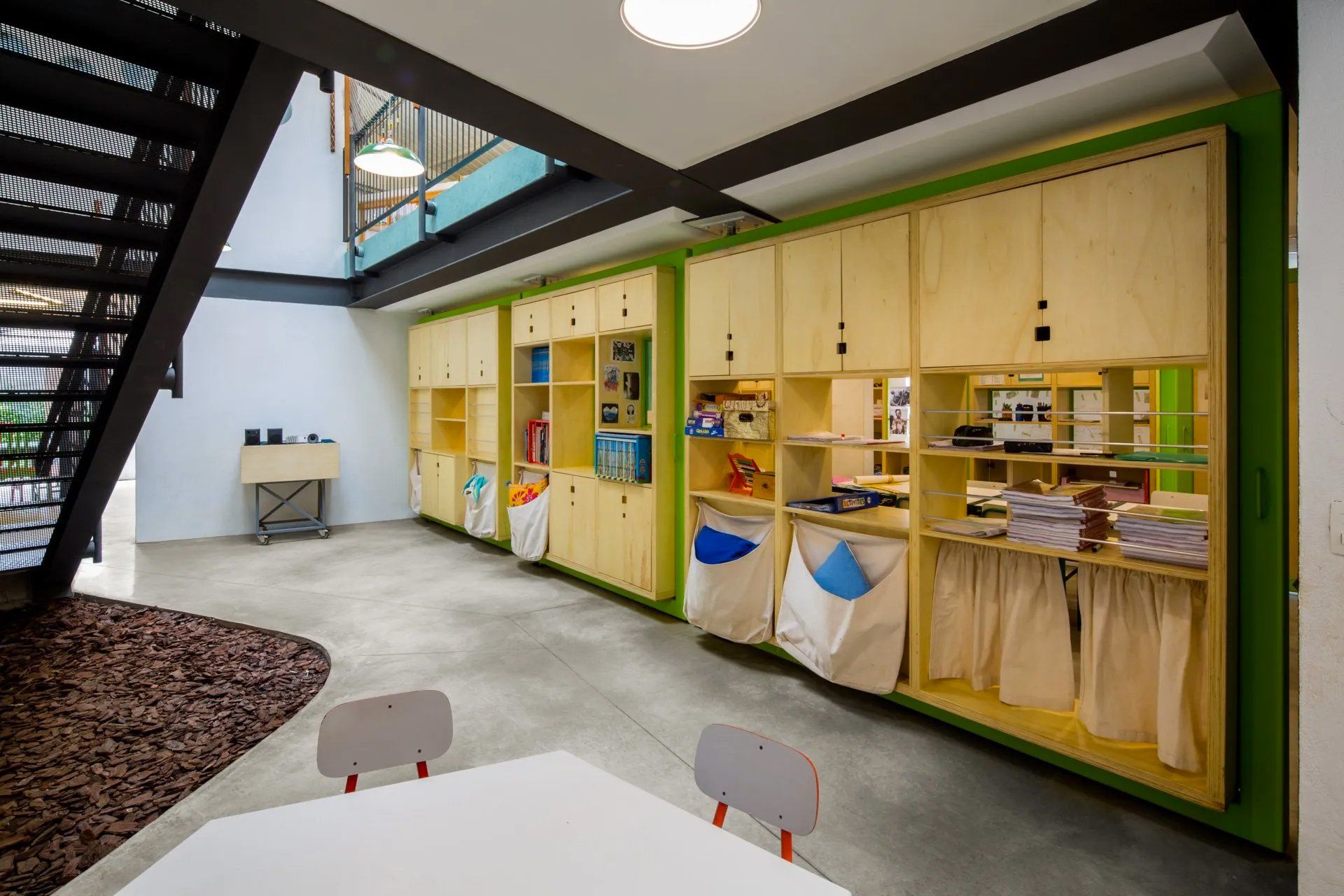 Uma sala com mesa e cadeiras e uma escada ao fundo