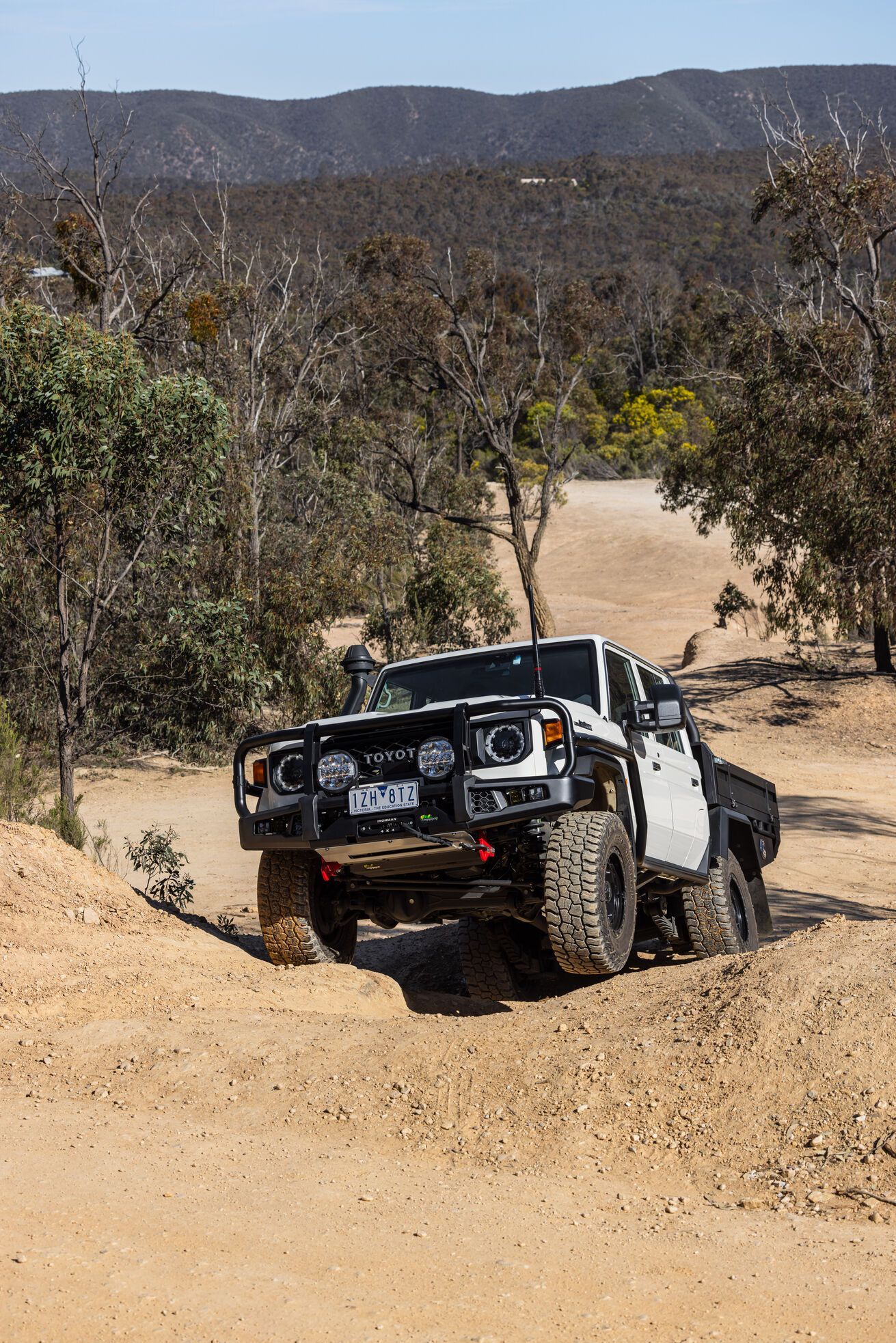 A white truck is driving down a dirt road.