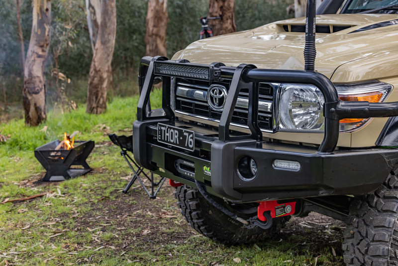 A toyota land cruiser is parked in a field next to a fire pit.