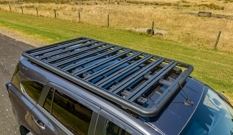 A black suv with a roof rack on top of it is parked on the side of the road.
