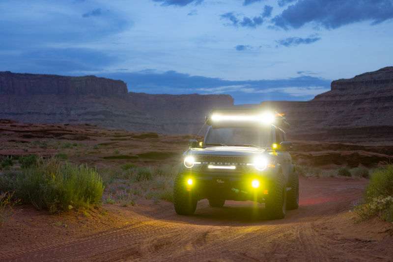 A truck is driving down a dirt road in the desert at night.