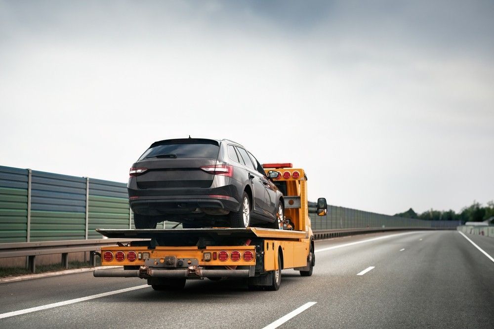 A Tow Truck is Towing a Car on a Highway — Kenny's Towing in Jensen, QLD