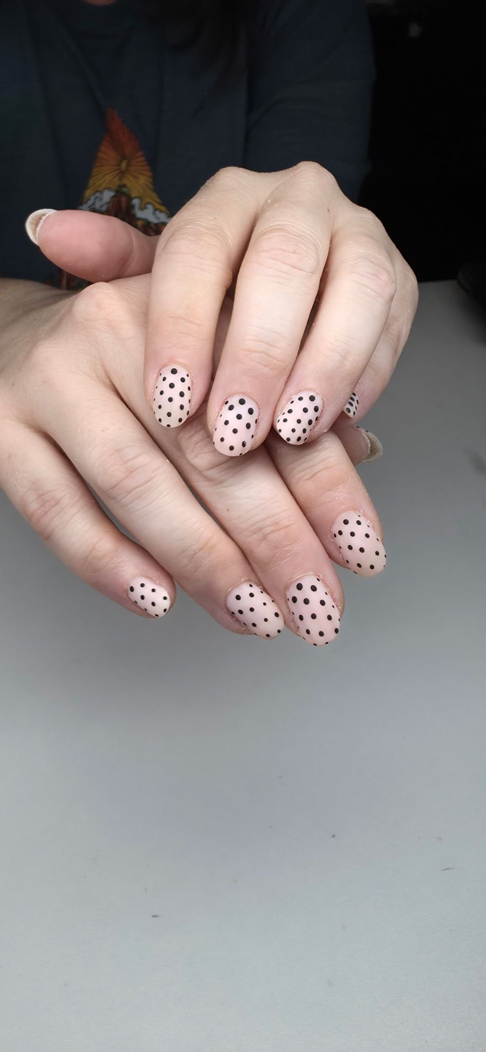 A close up of a woman 's hands with white polka dots on them.