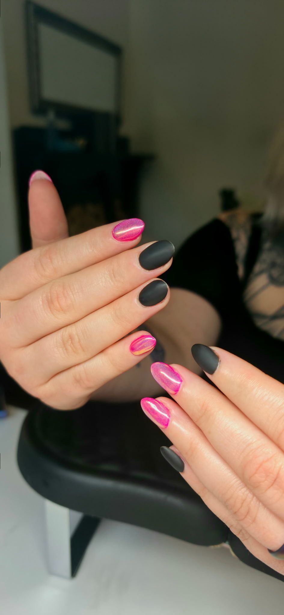 A close up of a woman 's hands with pink and black nails.