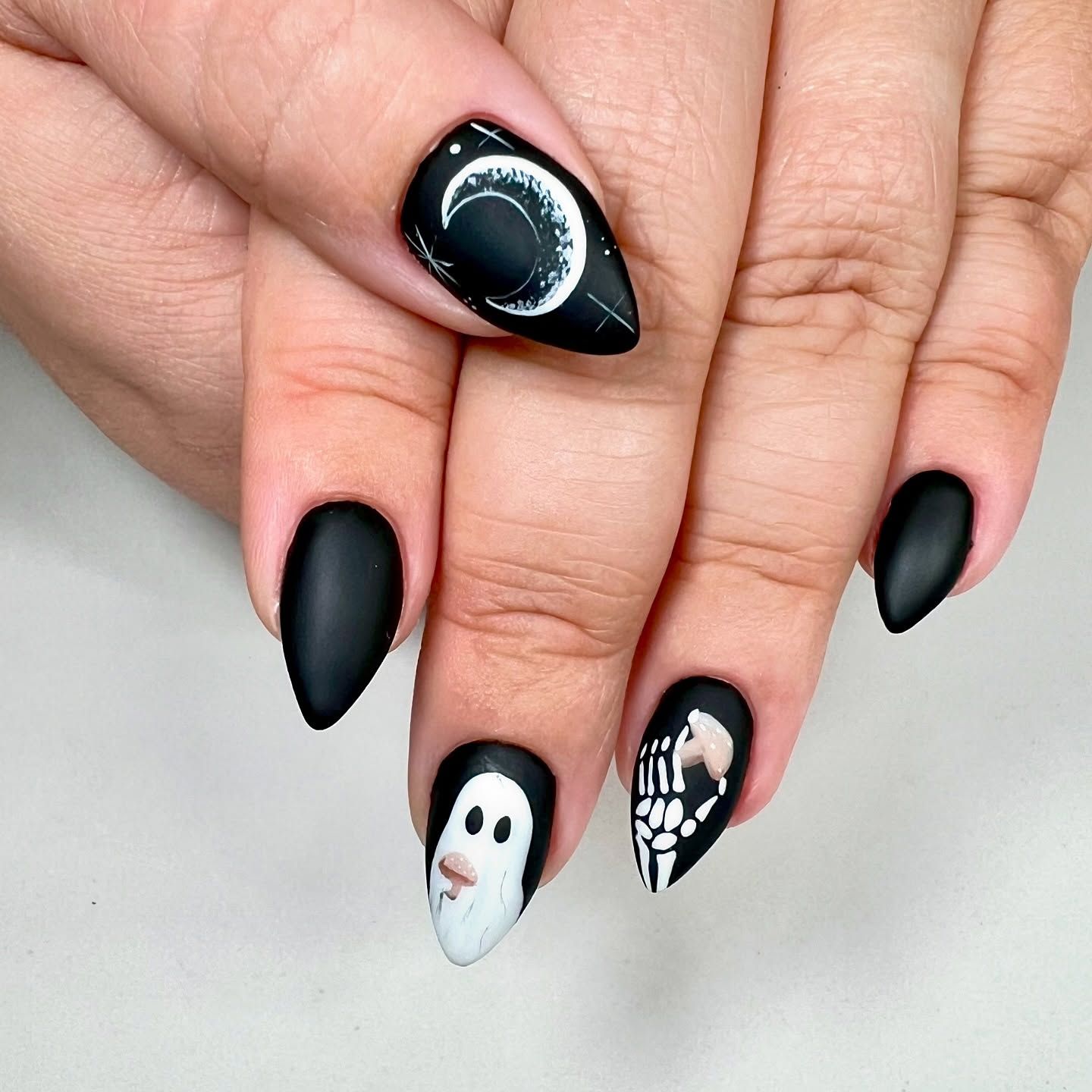 A close up of a person 's nails with a ghost and skeleton on them