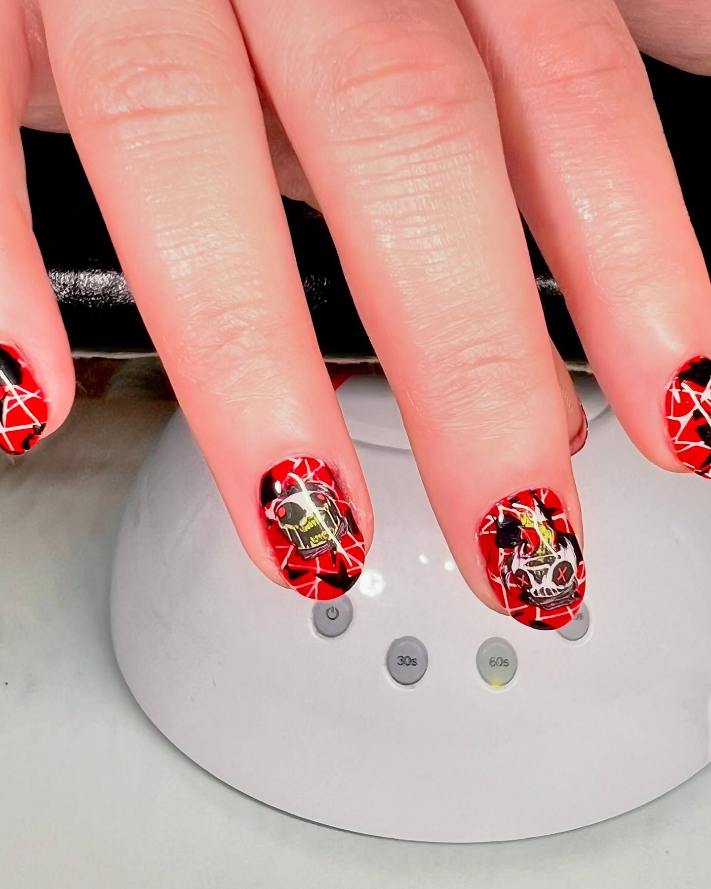 A close up of a person 's nails with red and black designs