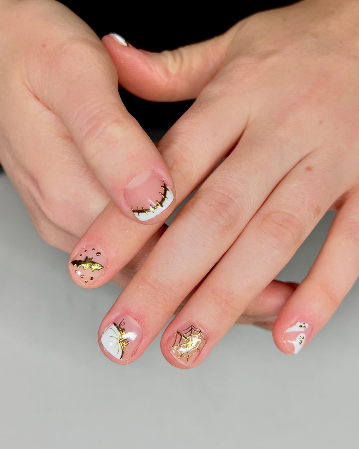 A close up of a person 's nails with white and gold designs