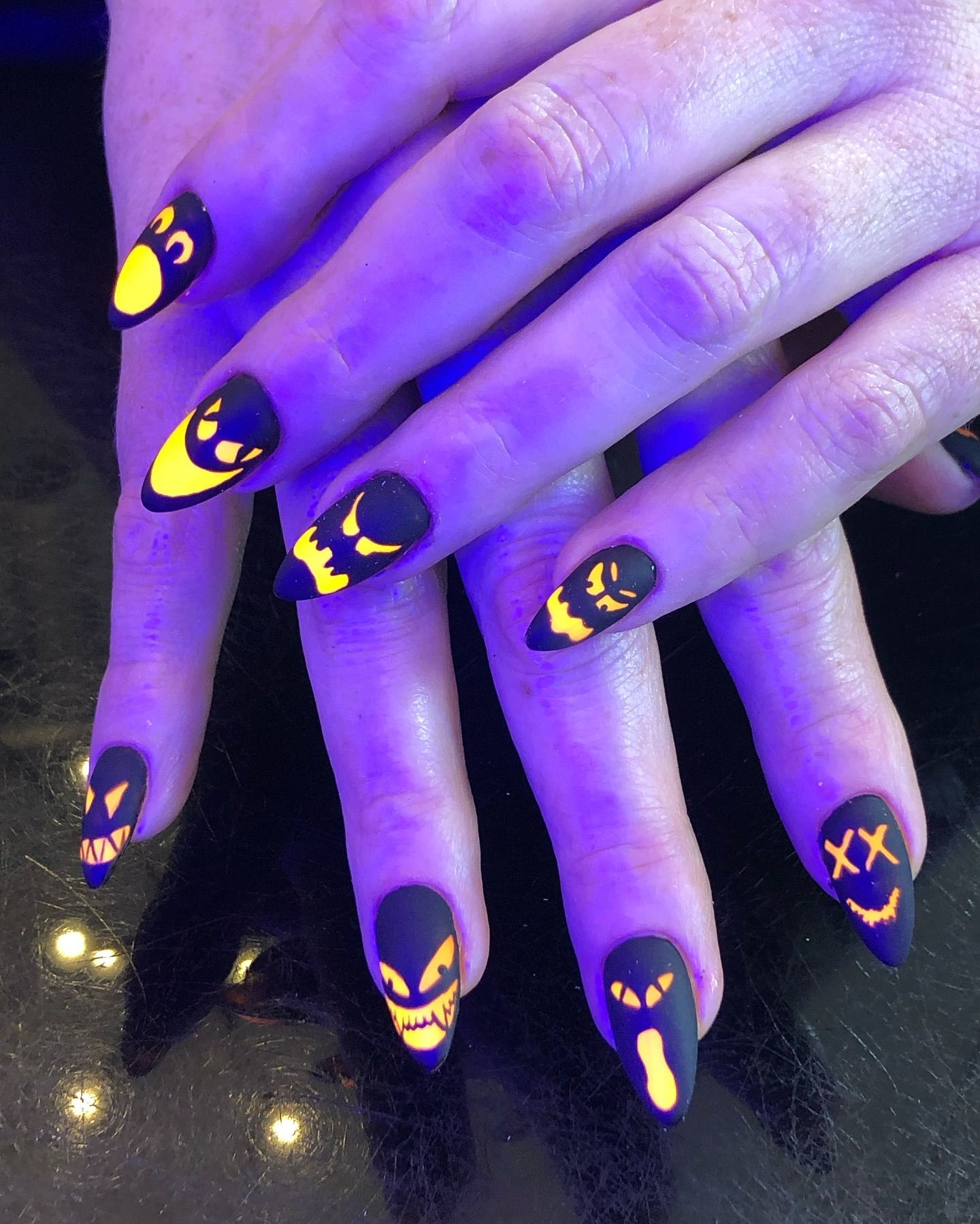 A close up of a person 's nails with glow in the dark designs