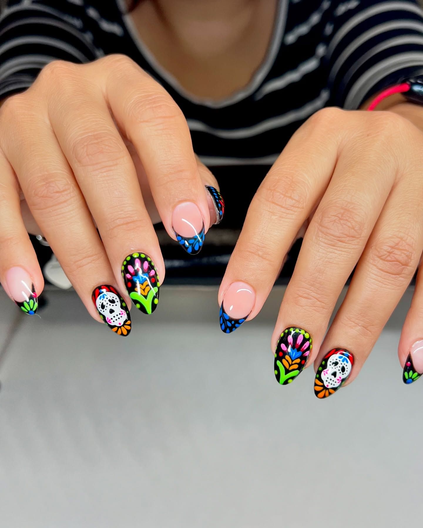 A woman 's nails are decorated with skulls and flowers