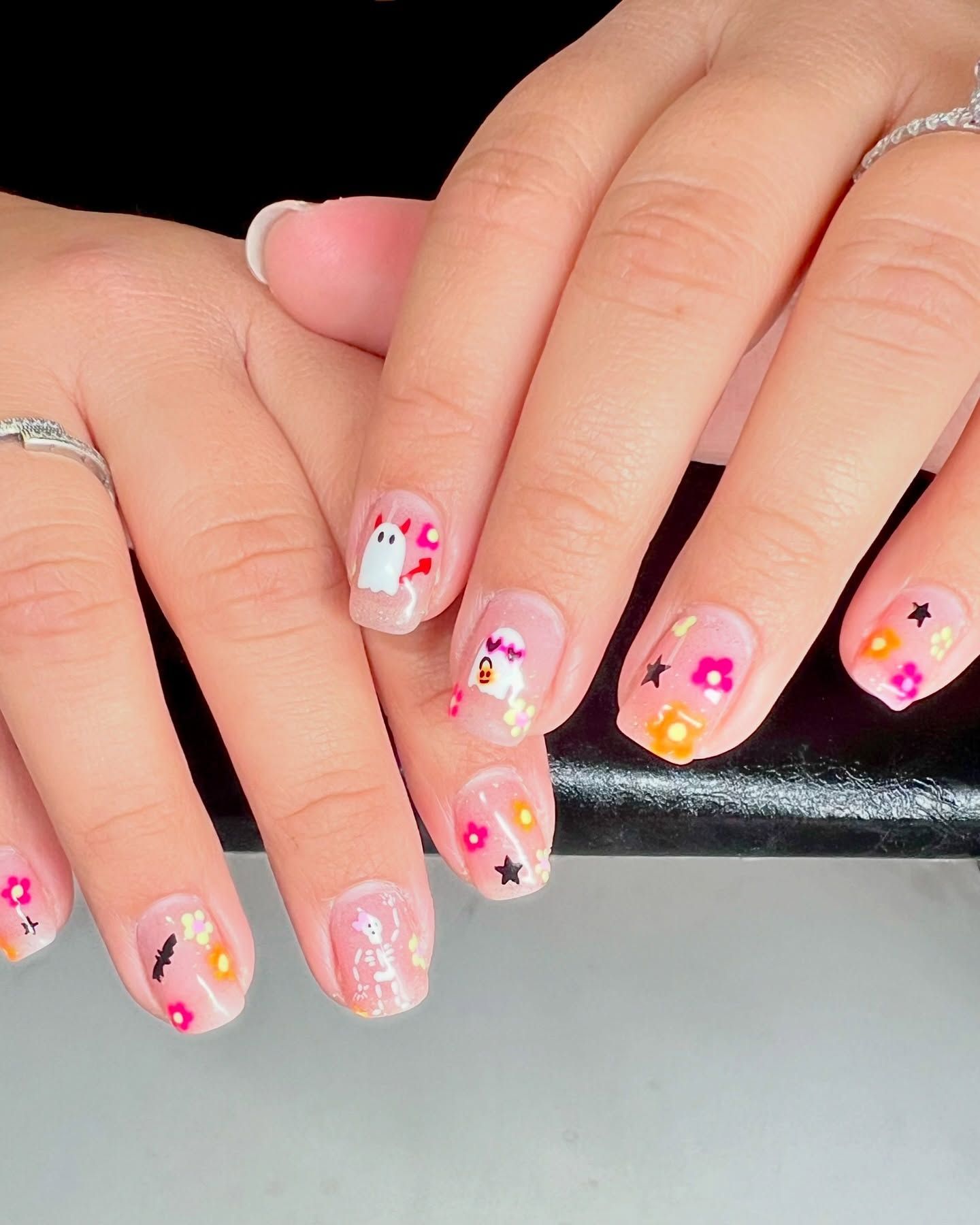 A woman 's nails are decorated with flowers and a ghost