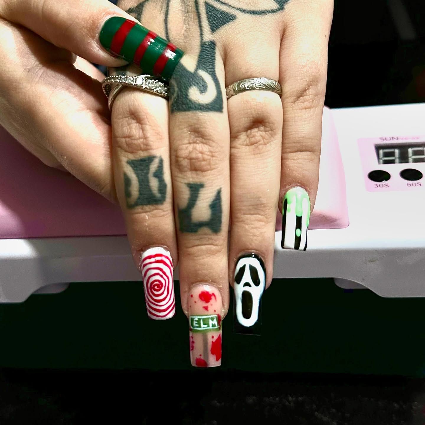 A close up of a woman 's nails with a tattoo on her hand