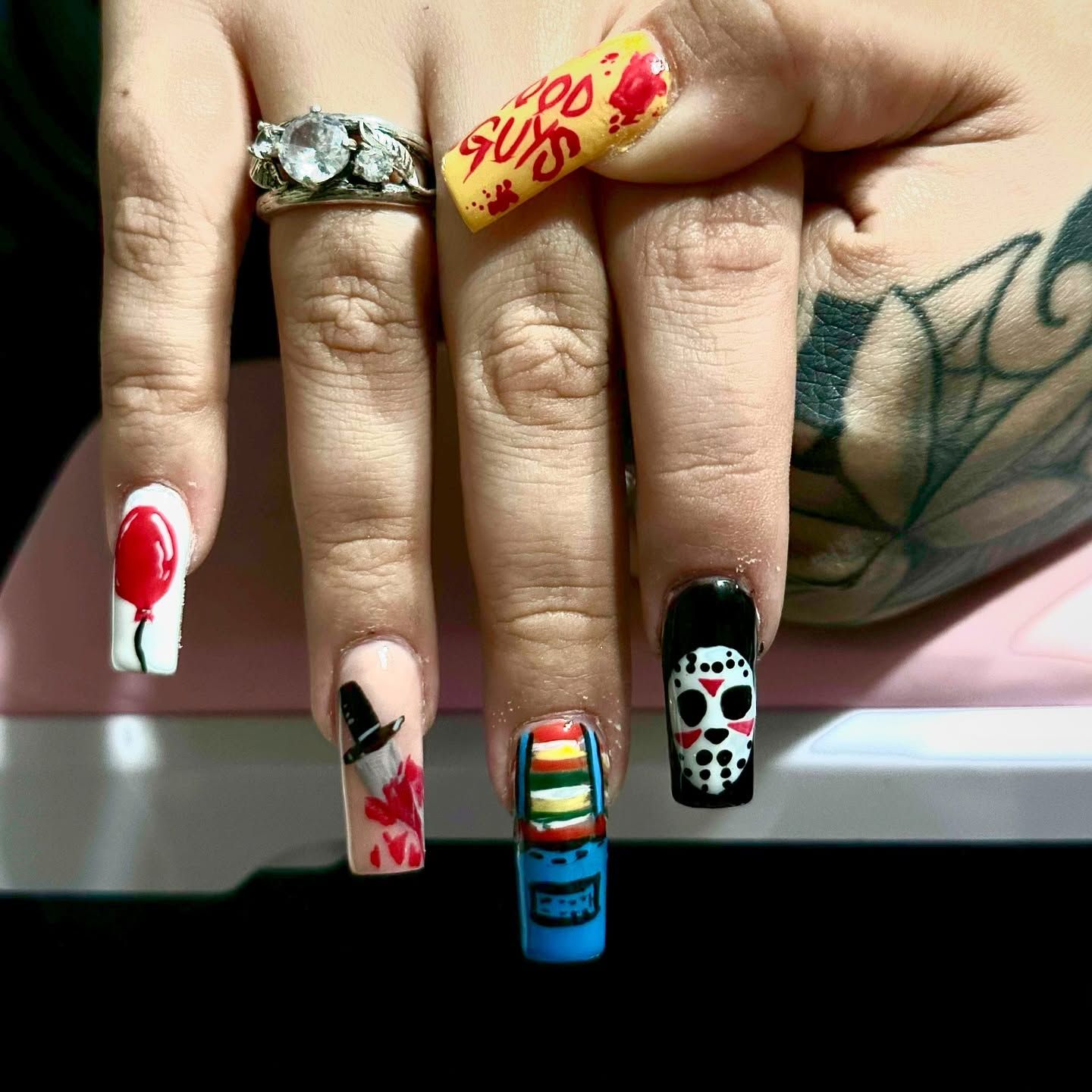 A close up of a woman 's nails with a tattoo on her hand.