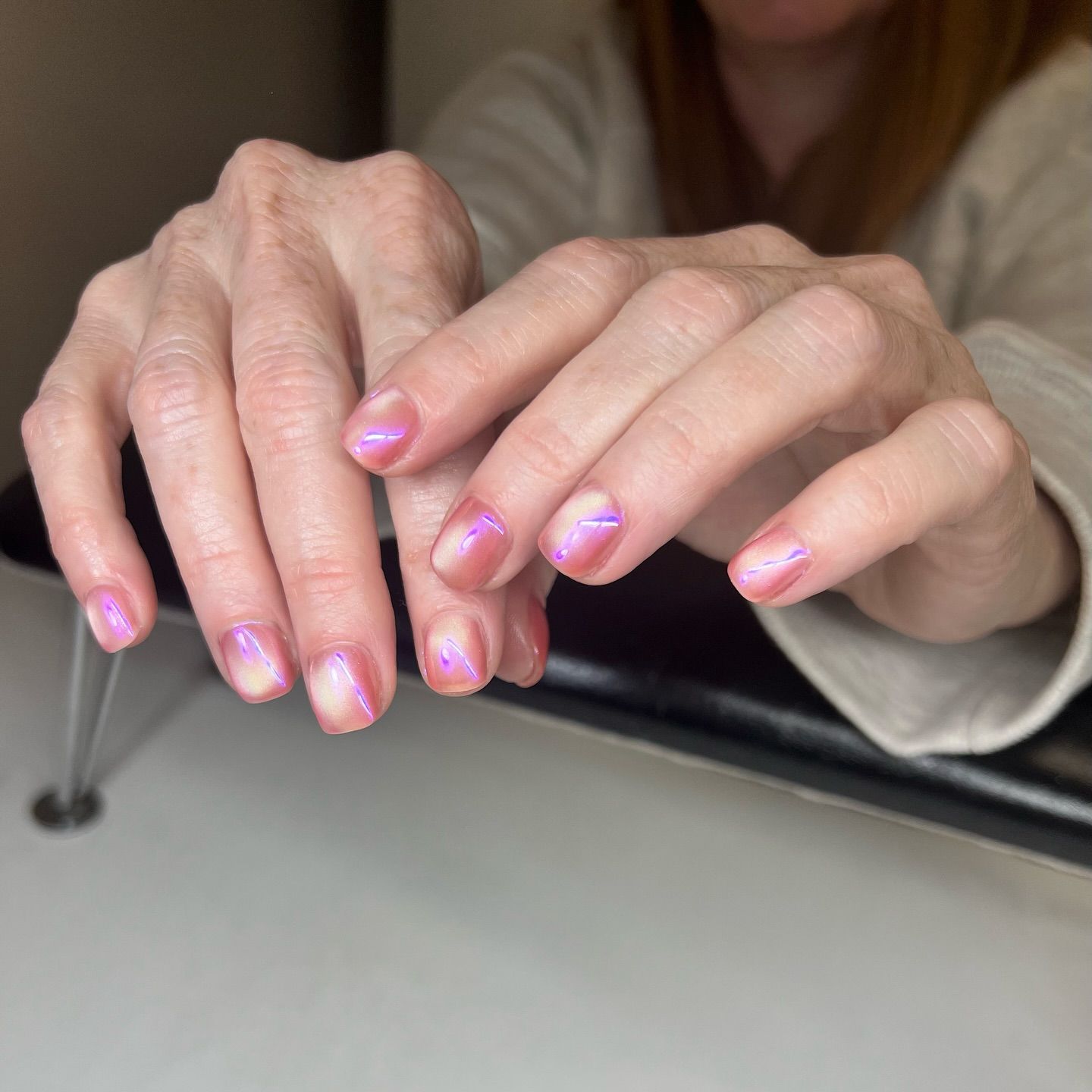 A close up of a woman 's hands with pink nail polish