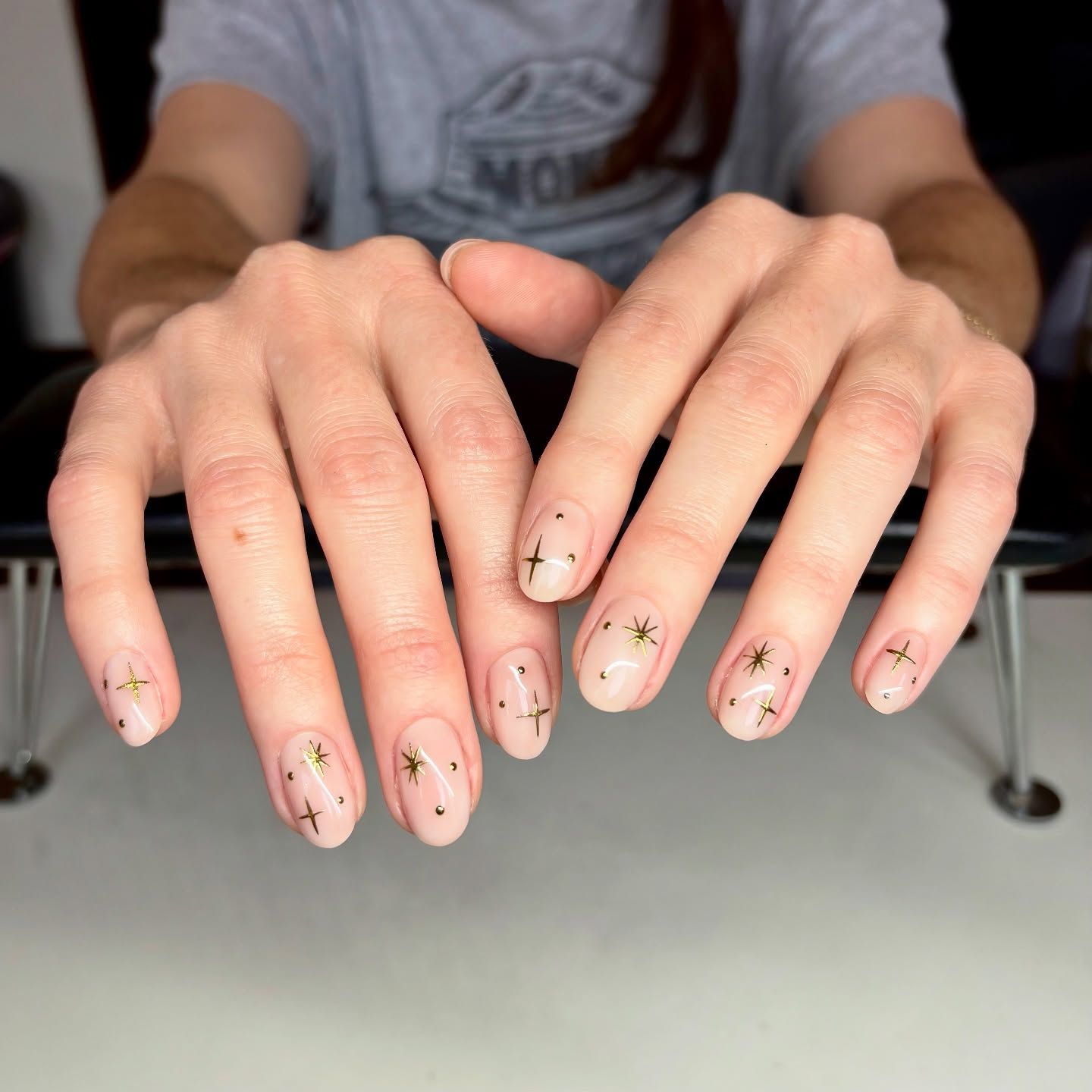 A close up of a woman 's nails with gold stars on them