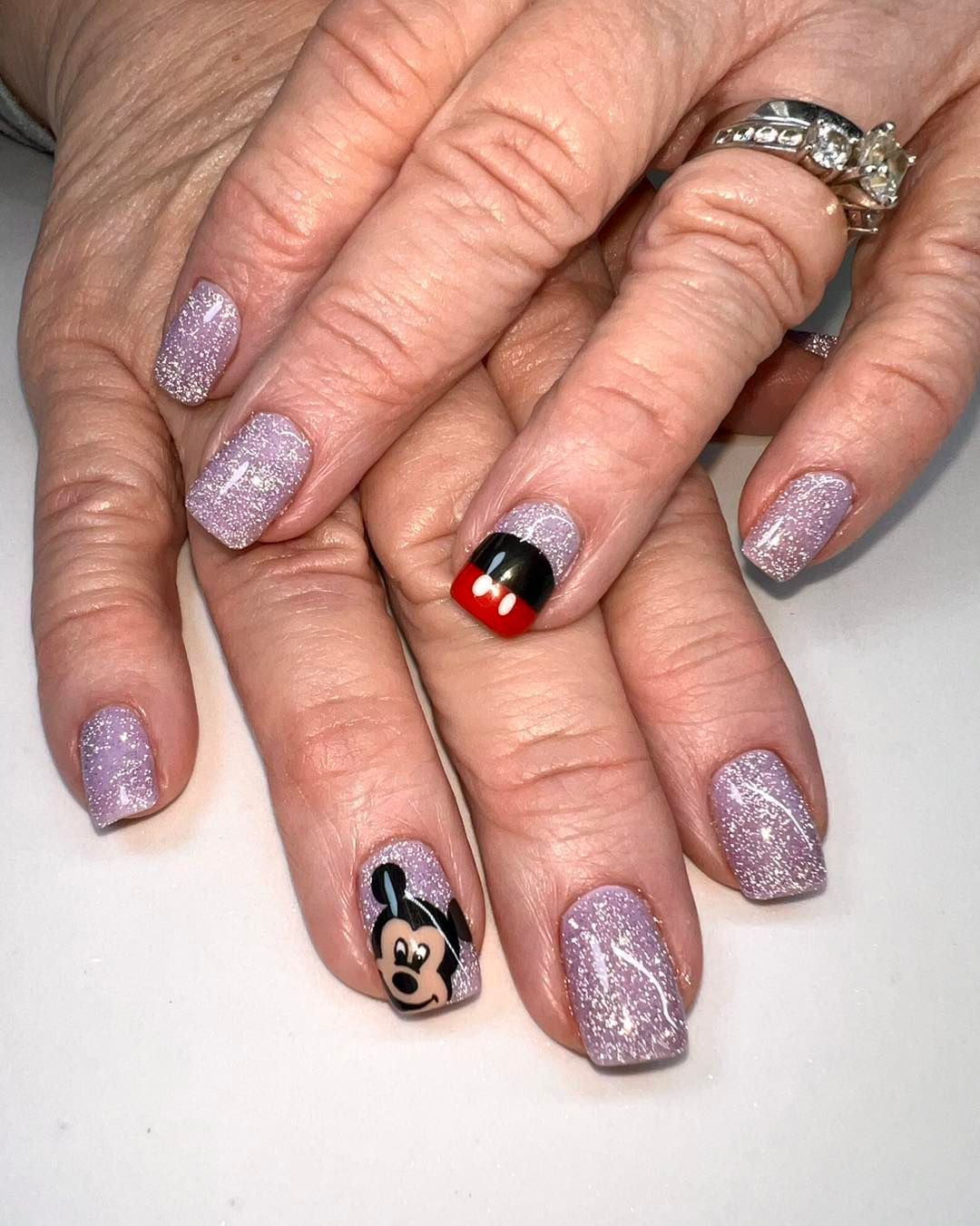 A close up of a woman 's nails with a mickey mouse design
