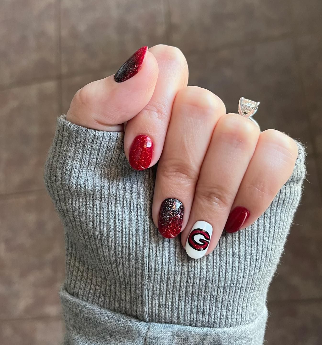 A woman 's hand with red and white nails and a ring on her finger