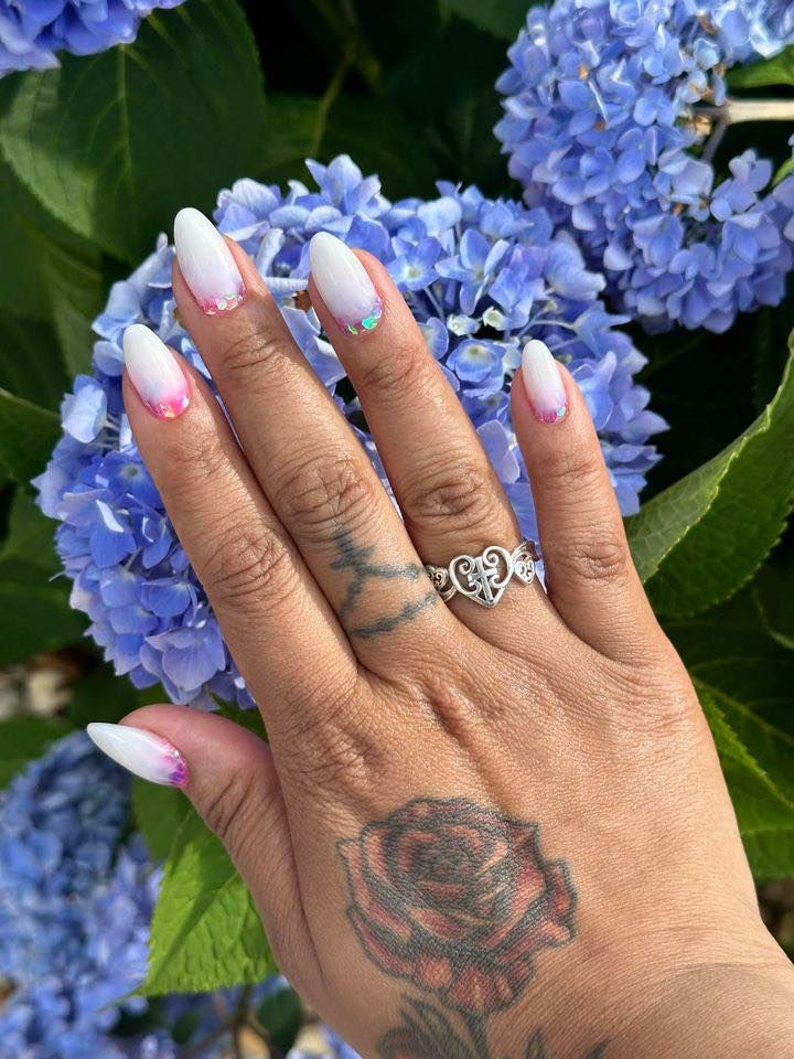 A woman 's hand with a tattoo and a ring on it is holding a flower.