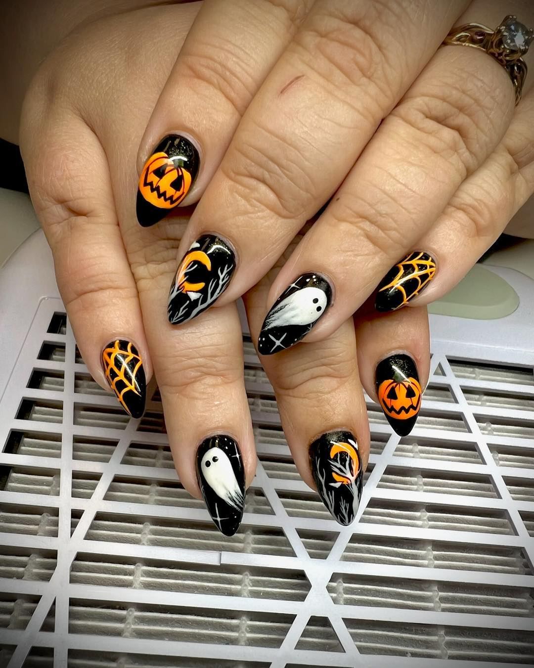 A woman 's nails are decorated with pumpkins and ghosts for halloween.