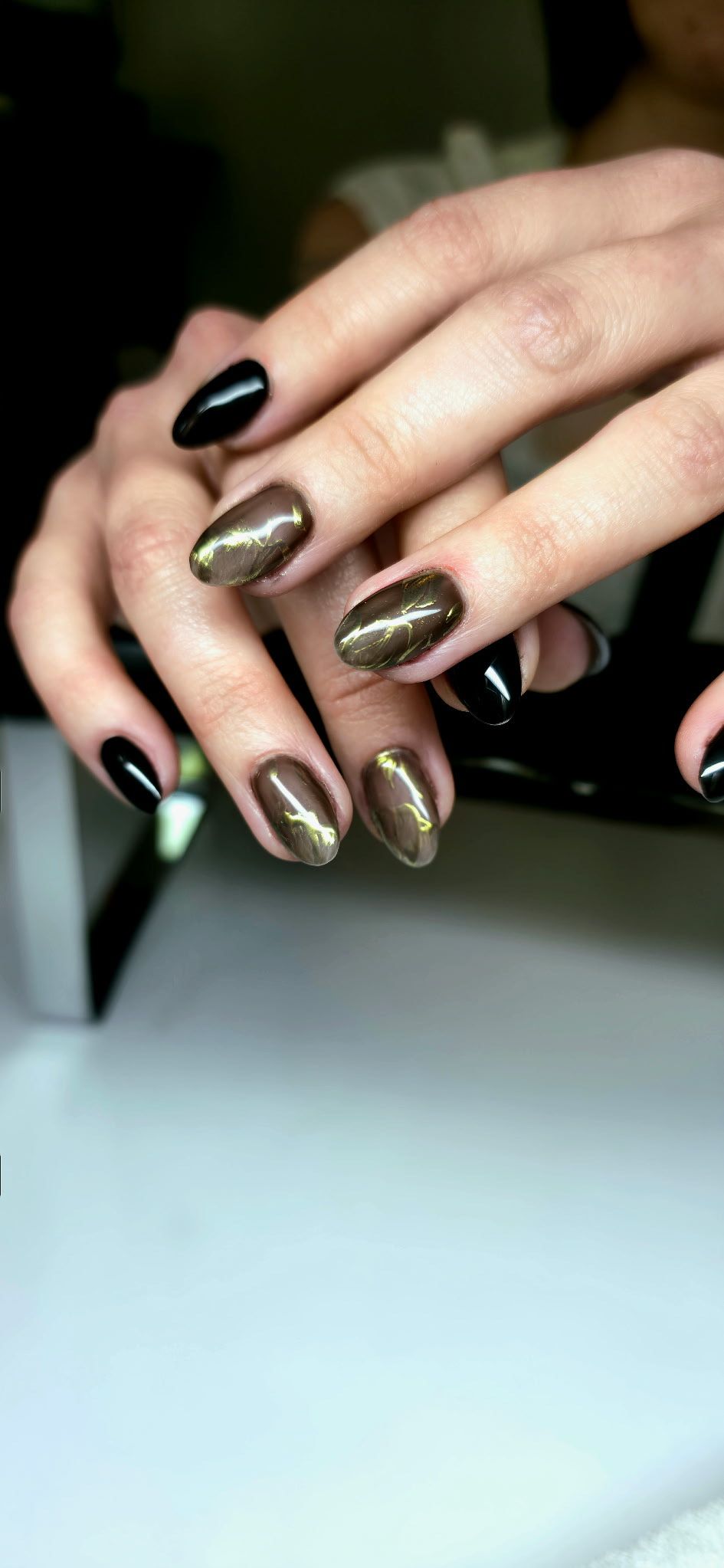 A close up of a woman 's hands with black and gold nails.
