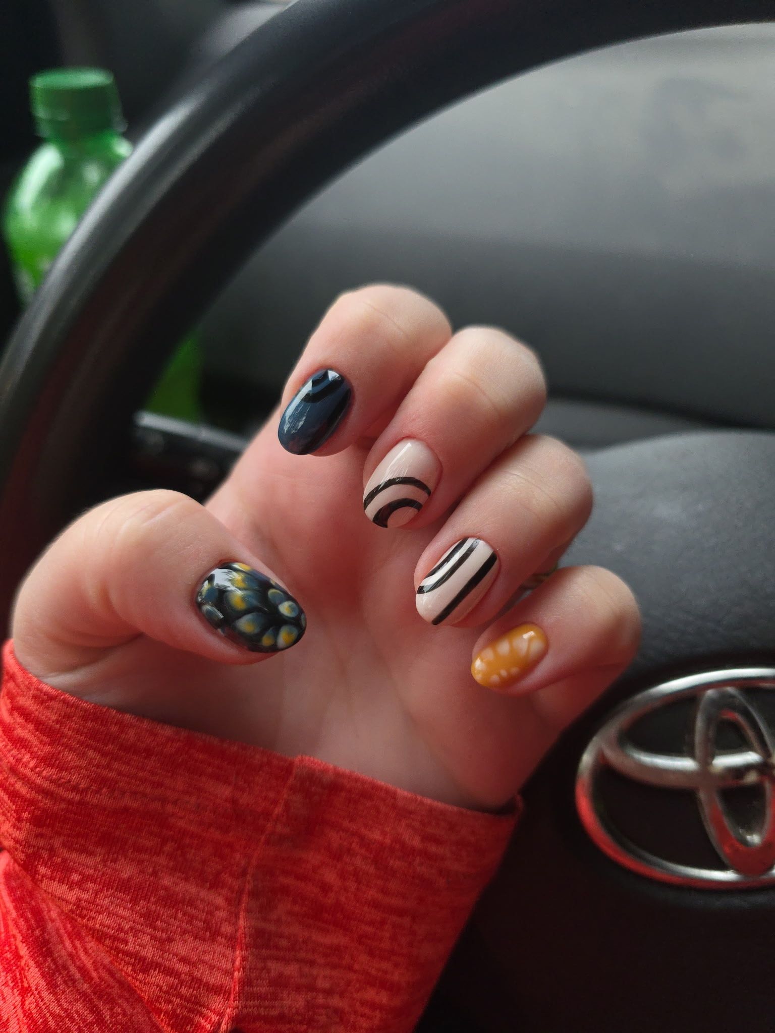 A close up of a person 's nails in a car with a toyota logo in the background.