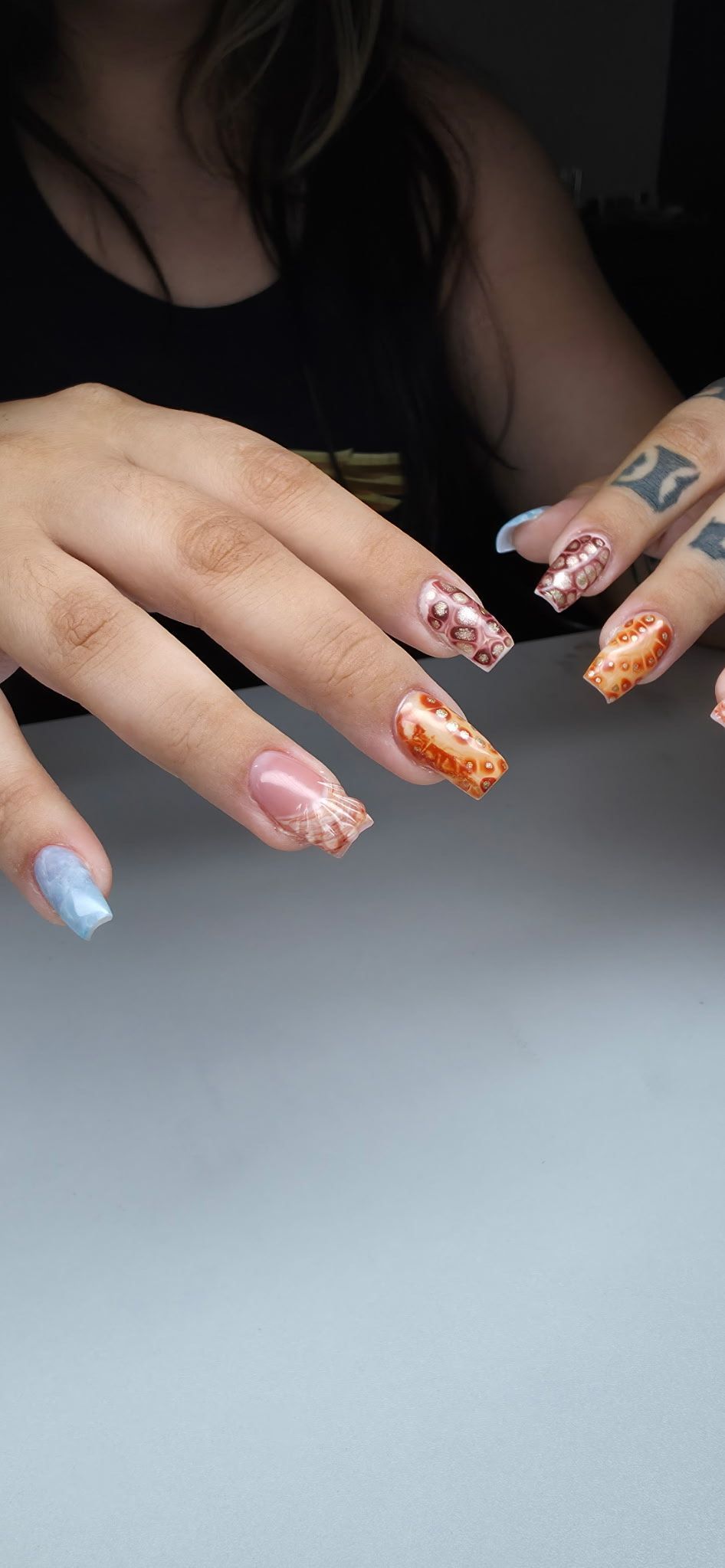 A close up of a woman 's nails with a tattoo on her finger.