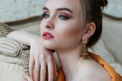 A woman wearing earrings and a bun is sitting on a couch.