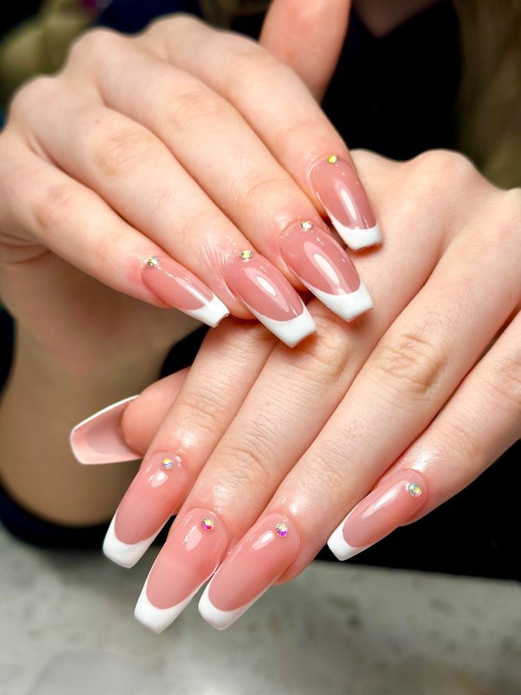 Hands with French manicure and pink glitter nail art resting together on a countertop