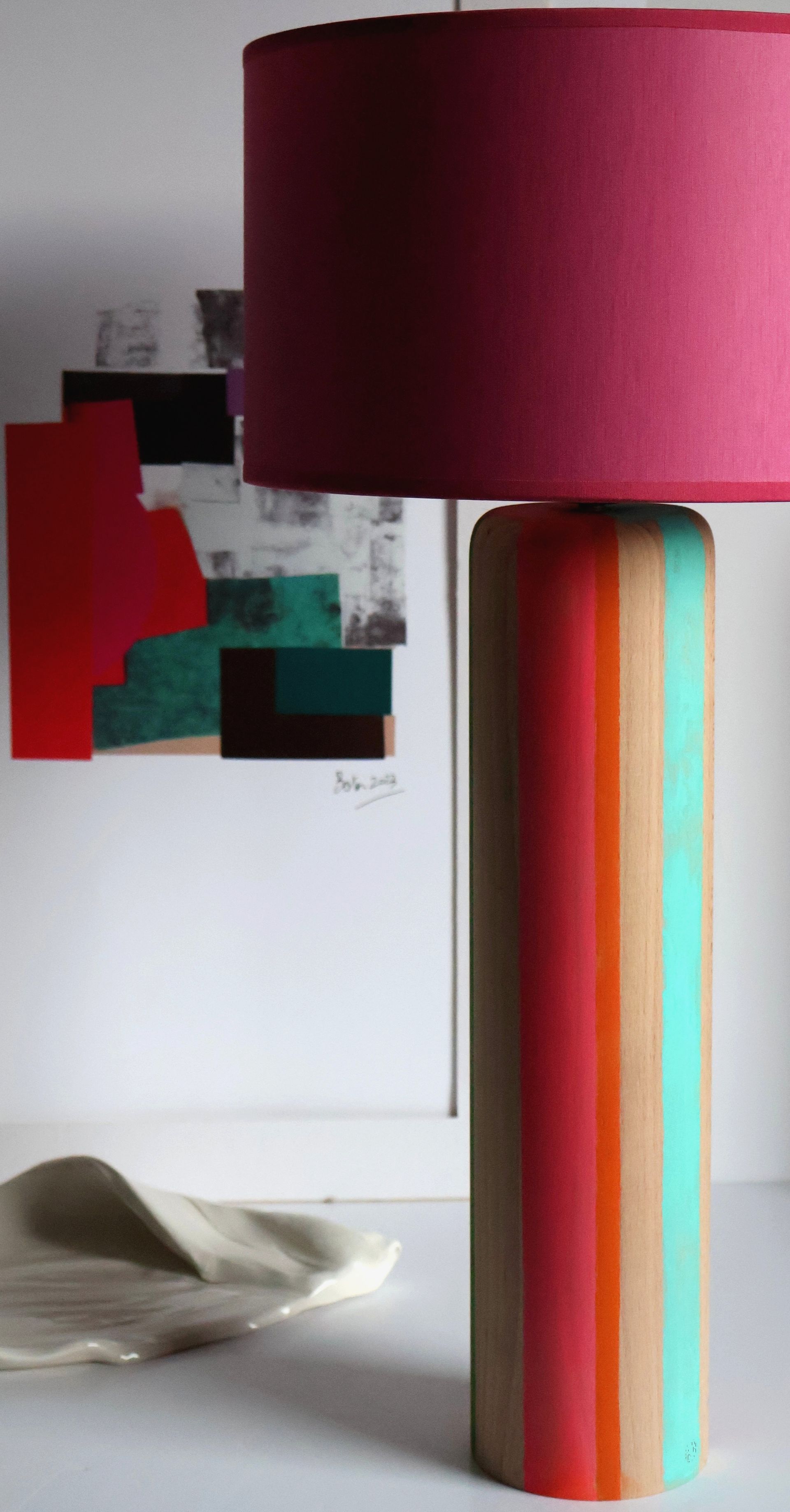 Una lámpara con pantalla rosa está sobre una mesa.