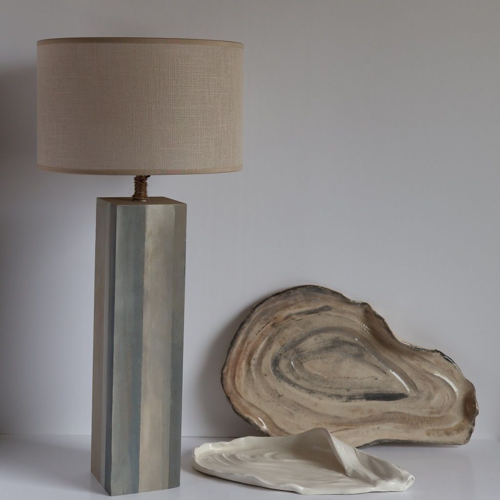 Una lámpara y un trozo de madera sobre una mesa.